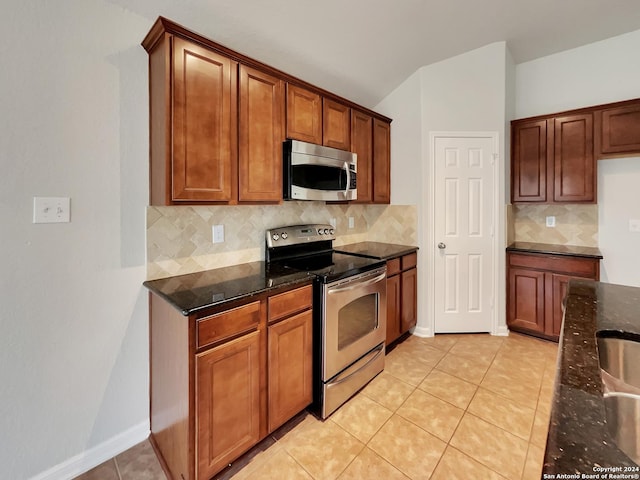 kitchen with dark stone countertops, light tile patterned floors, backsplash, and appliances with stainless steel finishes