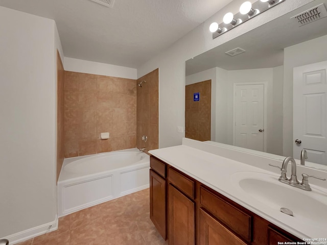 bathroom featuring a textured ceiling, vanity, tiled shower / bath, and tile patterned floors