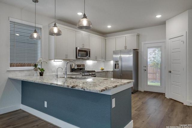 kitchen with hanging light fixtures, white cabinetry, appliances with stainless steel finishes, and kitchen peninsula