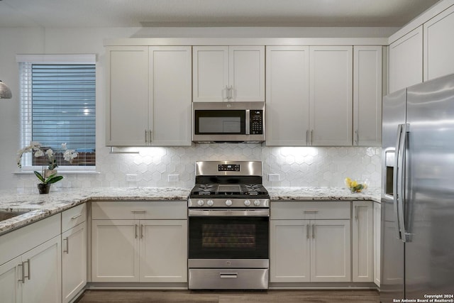 kitchen featuring white cabinetry, tasteful backsplash, appliances with stainless steel finishes, and light stone counters