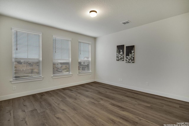 spare room with dark wood-type flooring and plenty of natural light