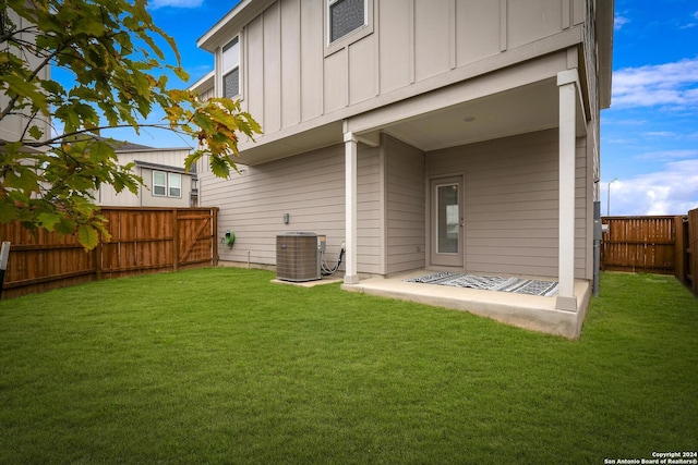 rear view of property featuring a yard, central AC unit, and a patio area