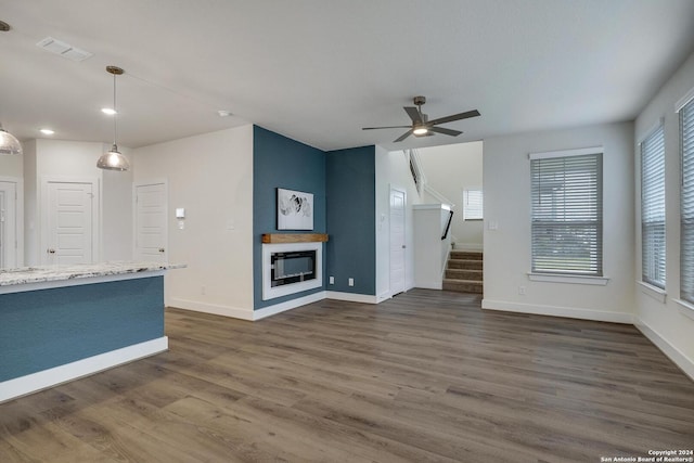 unfurnished living room featuring dark wood-type flooring, ceiling fan, and a fireplace