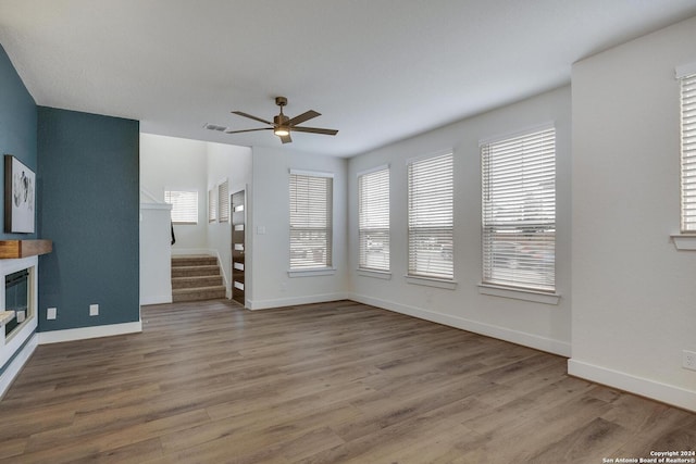 unfurnished living room with hardwood / wood-style flooring, ceiling fan, and a healthy amount of sunlight