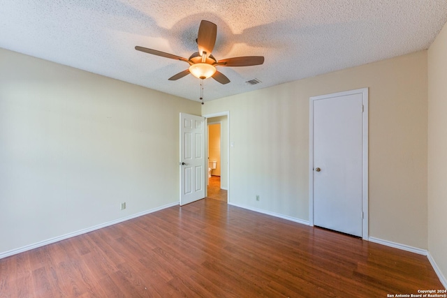 unfurnished room with a textured ceiling, ceiling fan, and dark wood-type flooring