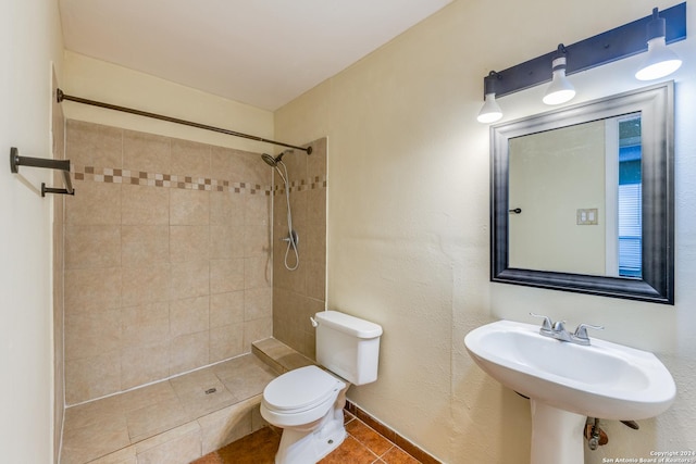 bathroom featuring toilet, tiled shower, tile patterned floors, and sink