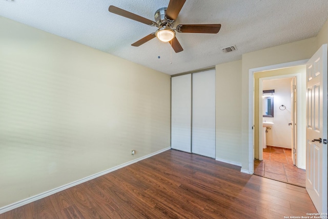 unfurnished bedroom featuring hardwood / wood-style floors, ceiling fan, a textured ceiling, and a closet