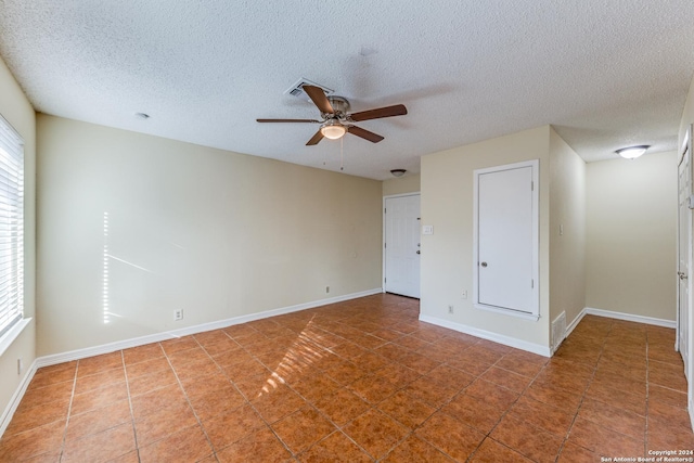 tiled spare room with ceiling fan and a textured ceiling