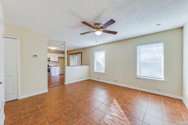 tiled spare room featuring a textured ceiling and ceiling fan