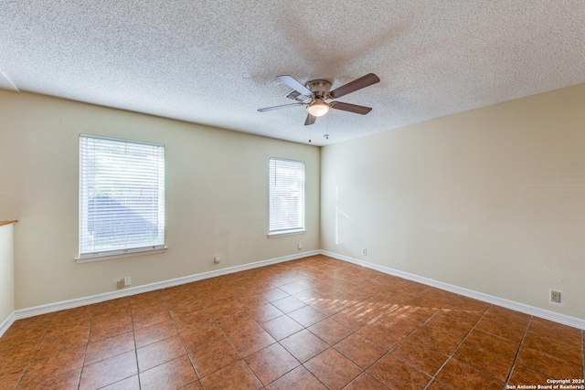 tiled spare room featuring a textured ceiling, plenty of natural light, and ceiling fan