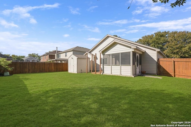 rear view of property featuring a lawn, a storage unit, and a sunroom