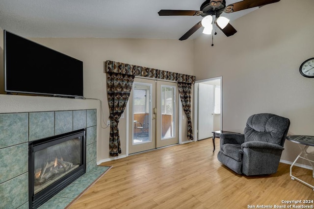 living area featuring a fireplace, light hardwood / wood-style floors, ceiling fan, and lofted ceiling