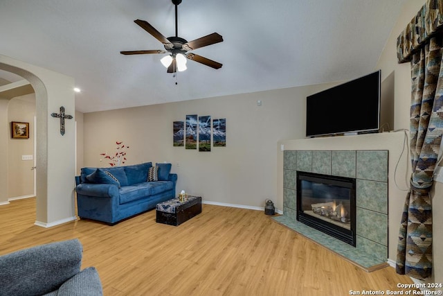 living room with a tile fireplace, ceiling fan, and light hardwood / wood-style flooring