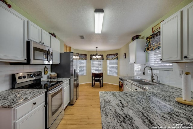 kitchen featuring decorative backsplash, sink, appliances with stainless steel finishes, and light hardwood / wood-style flooring