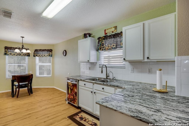 kitchen featuring white cabinetry, decorative backsplash, sink, and a healthy amount of sunlight