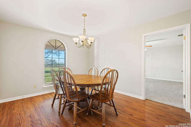 dining area with hardwood / wood-style flooring and an inviting chandelier