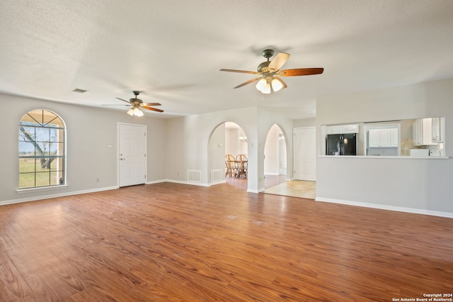 unfurnished living room with ceiling fan, light hardwood / wood-style floors, and a textured ceiling