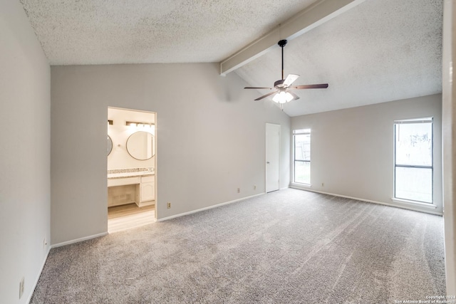 interior space featuring vaulted ceiling with beams, ensuite bath, multiple windows, and ceiling fan