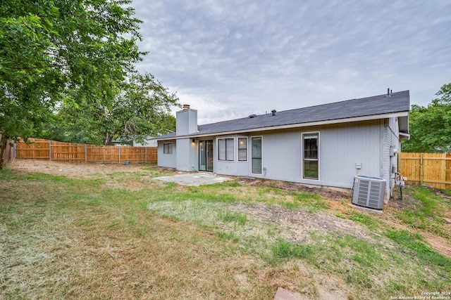 rear view of property featuring central air condition unit and a yard