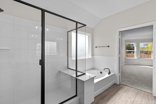 bathroom featuring hardwood / wood-style floors, independent shower and bath, and vaulted ceiling