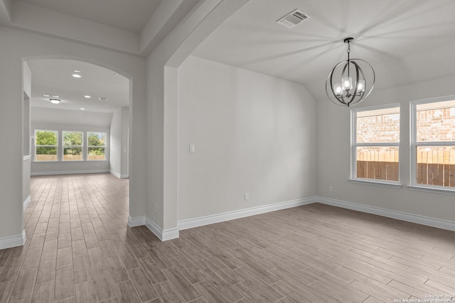 unfurnished room with an inviting chandelier, a healthy amount of sunlight, and light hardwood / wood-style floors