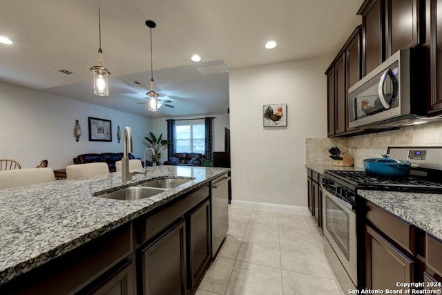 kitchen with backsplash, sink, light stone counters, dark brown cabinetry, and stainless steel appliances