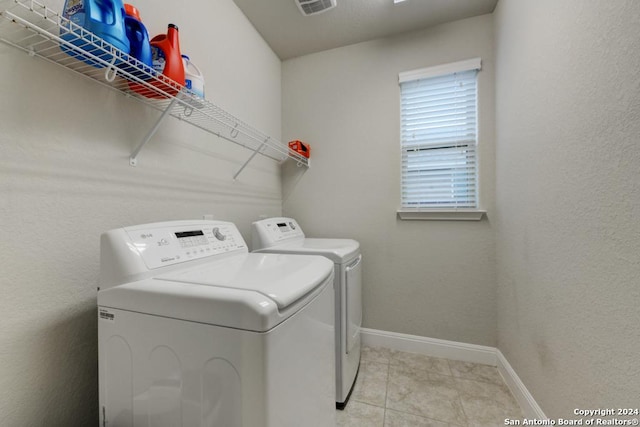 clothes washing area featuring washer and clothes dryer and light tile patterned flooring