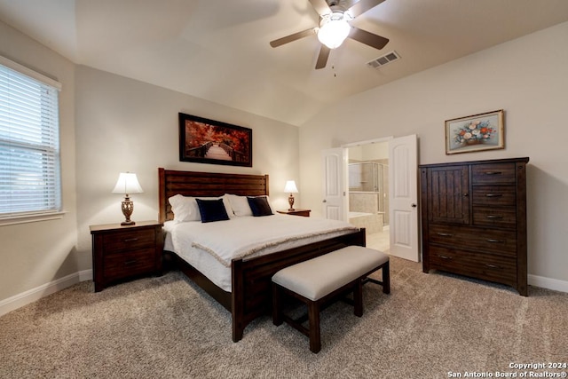 bedroom with ceiling fan, light colored carpet, lofted ceiling, and ensuite bath