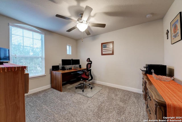 office space featuring plenty of natural light, ceiling fan, and light carpet