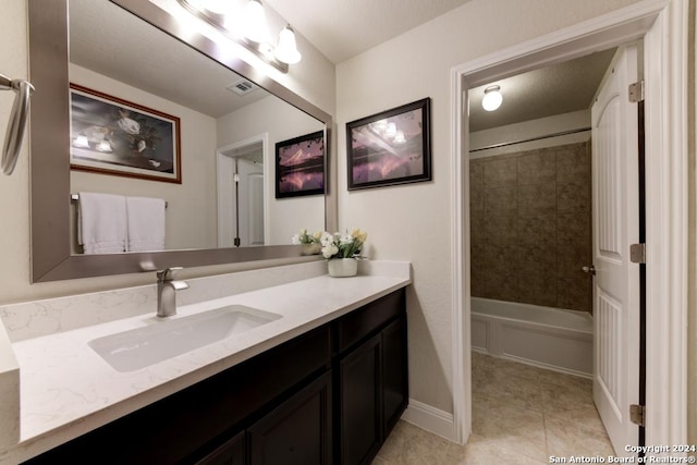 bathroom with tile patterned floors, vanity, and tiled shower / bath