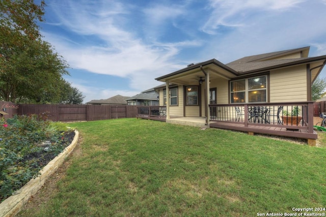 rear view of property with a lawn, ceiling fan, and a wooden deck