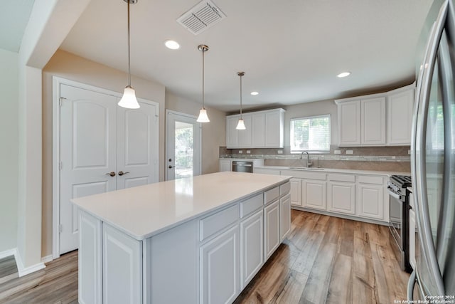 kitchen featuring pendant lighting, white cabinets, light hardwood / wood-style flooring, tasteful backsplash, and a kitchen island