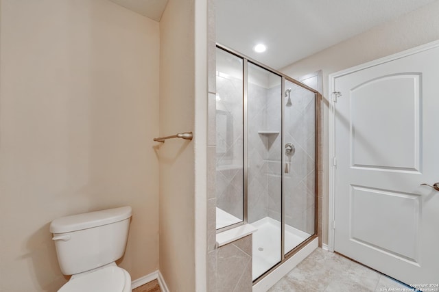 bathroom featuring tile patterned flooring, toilet, and an enclosed shower