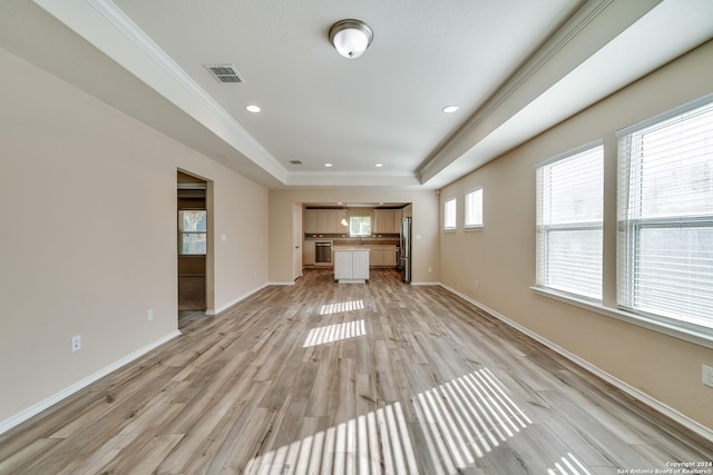 unfurnished living room with a tray ceiling, crown molding, and light wood-type flooring