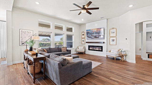 living room with a large fireplace, hardwood / wood-style flooring, and ceiling fan