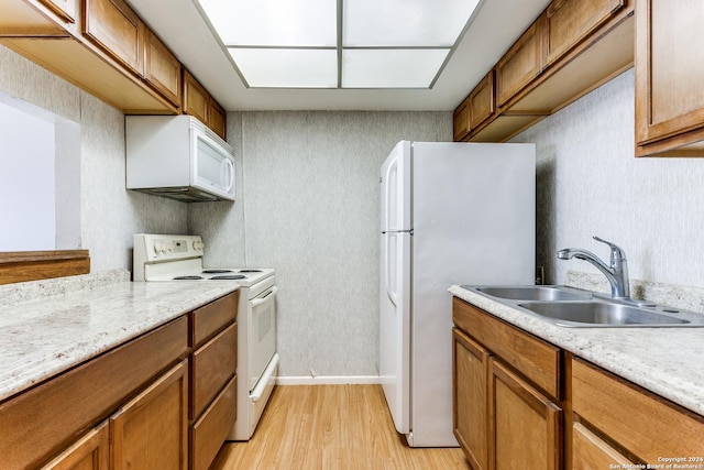 kitchen featuring light stone countertops, sink, light hardwood / wood-style floors, and white appliances