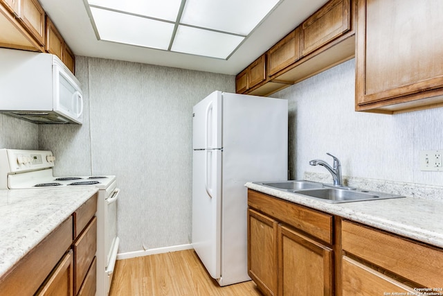 kitchen featuring white appliances, sink, and light hardwood / wood-style flooring