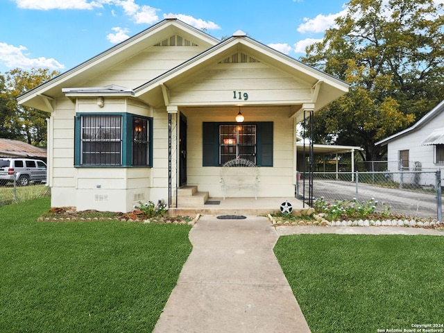 bungalow-style house featuring covered porch and a front yard