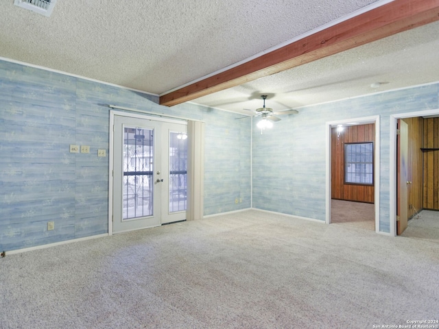 empty room featuring beamed ceiling, light colored carpet, a textured ceiling, and french doors