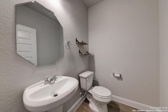 bathroom featuring toilet, wood-type flooring, and sink