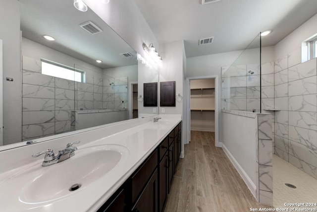 bathroom with hardwood / wood-style floors, vanity, and a tile shower