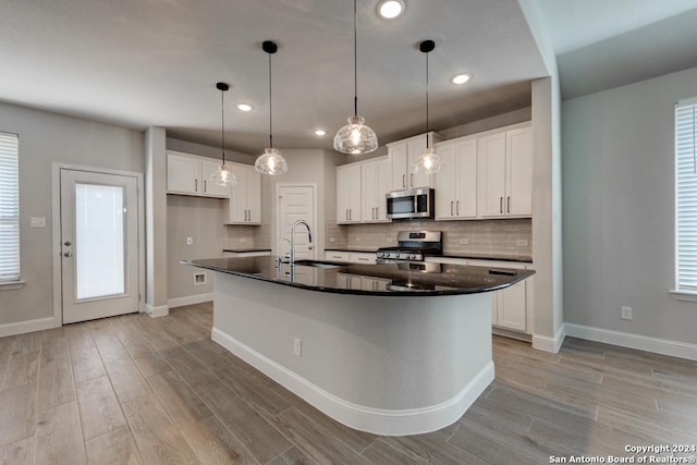 kitchen with white cabinets, stainless steel appliances, and a kitchen island with sink