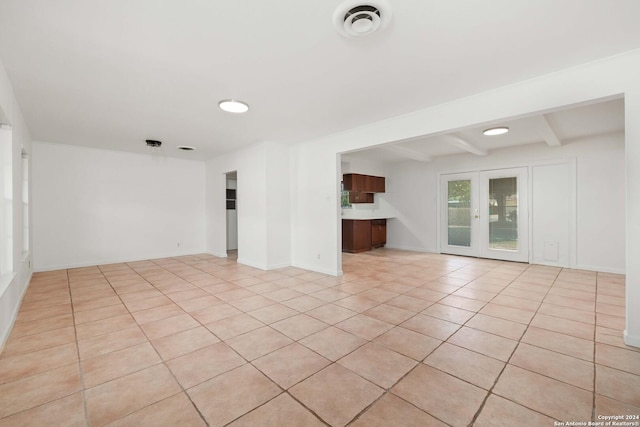 tiled empty room featuring beam ceiling