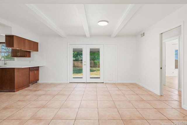 kitchen with french doors, beamed ceiling, light tile patterned flooring, and sink