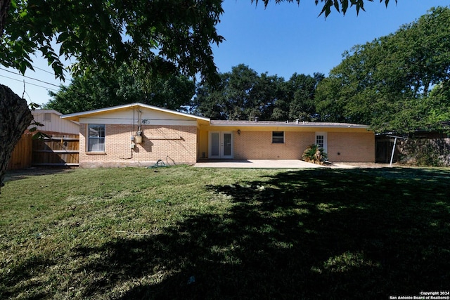 rear view of property featuring french doors, a patio, and a lawn