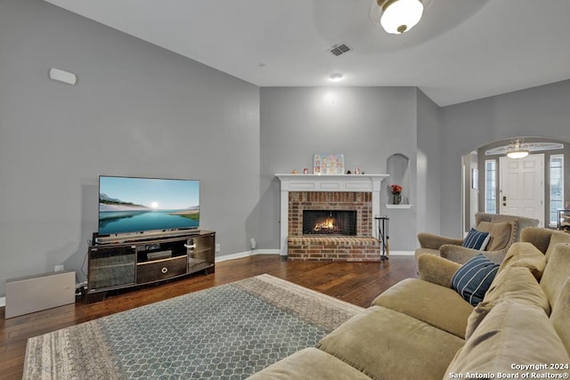 living room featuring dark hardwood / wood-style floors, ceiling fan, a fireplace, and vaulted ceiling