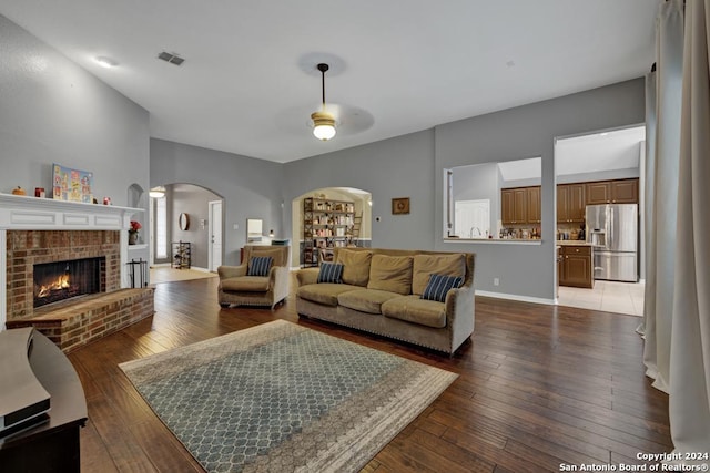 living room featuring ceiling fan, dark hardwood / wood-style flooring, and a fireplace