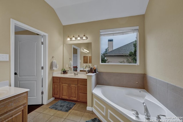 bathroom featuring tile patterned flooring, vanity, a bathtub, and vaulted ceiling