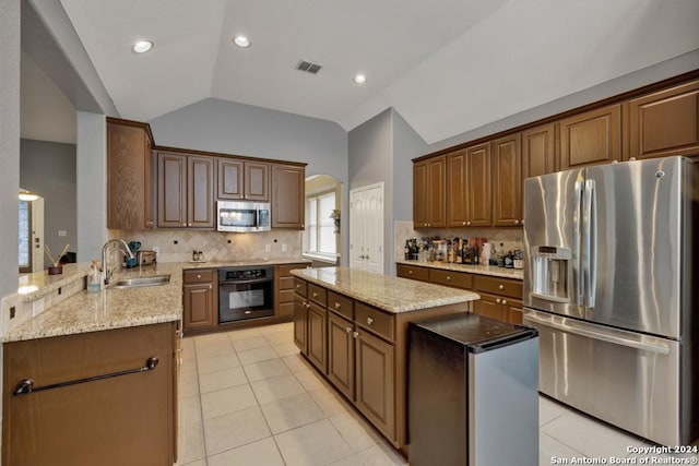 kitchen with a center island, lofted ceiling, sink, appliances with stainless steel finishes, and kitchen peninsula