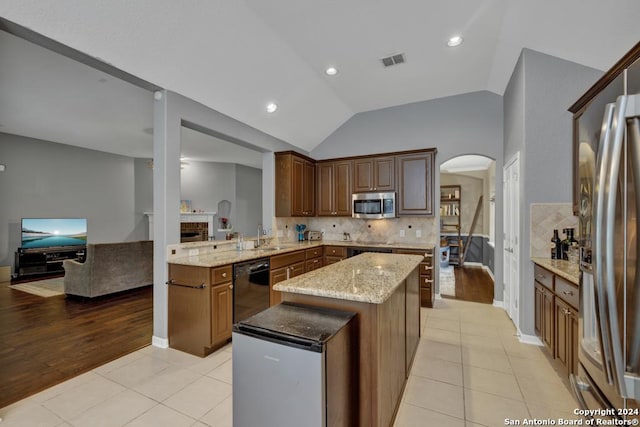 kitchen featuring kitchen peninsula, appliances with stainless steel finishes, light wood-type flooring, and vaulted ceiling